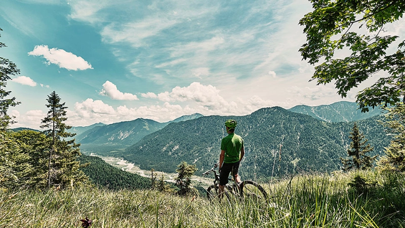 Mountainbiker auf Bergwiese mit Aussicht ins Tal