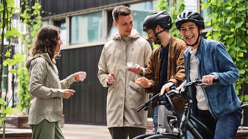 Ein JobRad Team aus vier Personen trinkt Kaffee auf dem JobRad-Campus, eine Frau aus dem Team sitzt auf dem Fahrrad Ein JobRad Team aus vier Personen trinkt Kaffee auf dem JobRad-Campus, eine Frau aus dem Team sitzt auf dem Fahrrad